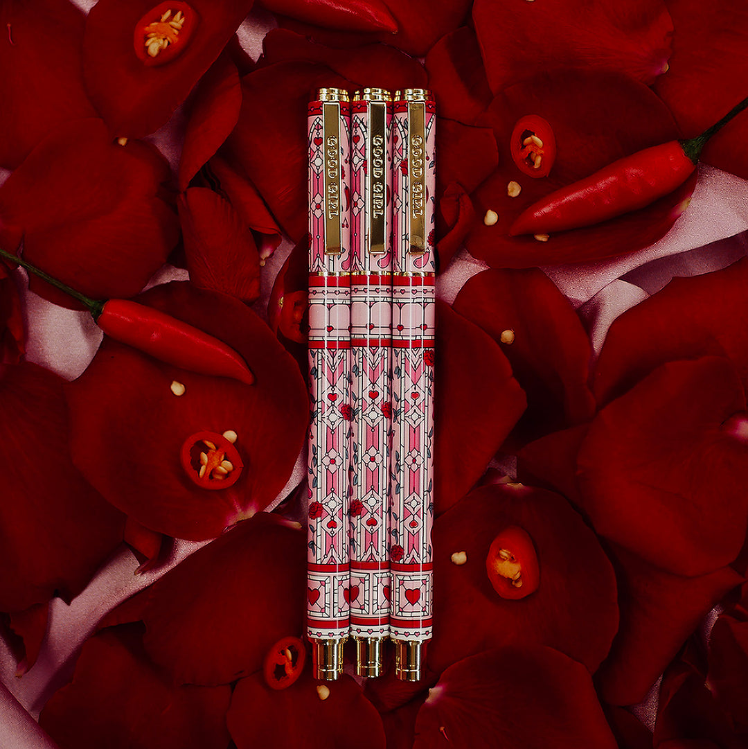 Good Girl - Pink Pen - Black Ink - The Quirky Cup Collective - Stained Glass Inspired Pen Design with 'Bite me' engraved on the pen clip. Pen sits on a bed of red rose petals. 