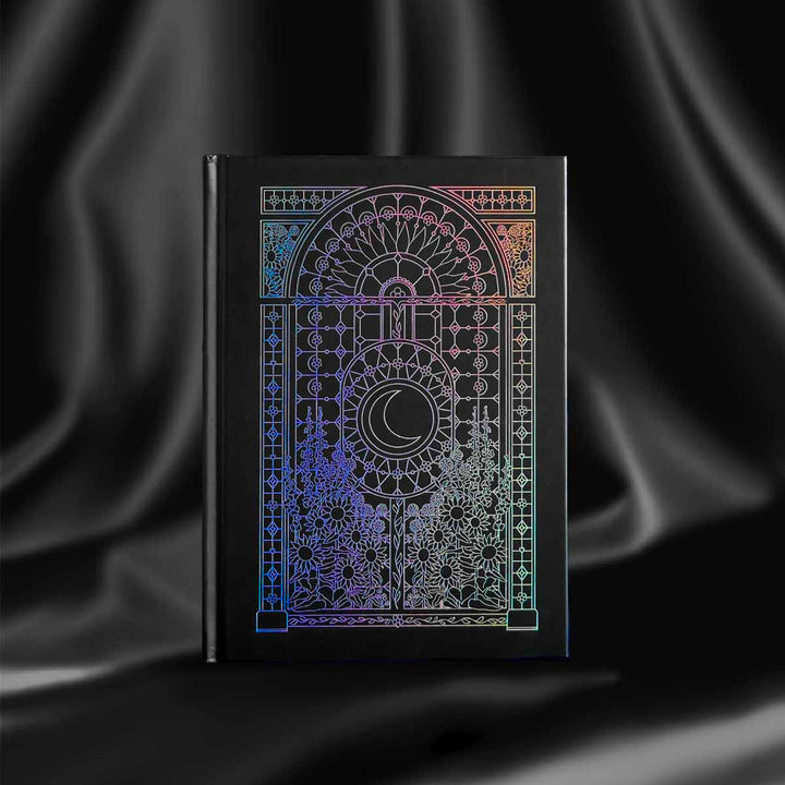 decorative black journal with holographic foiling sits on a background of black draped silk