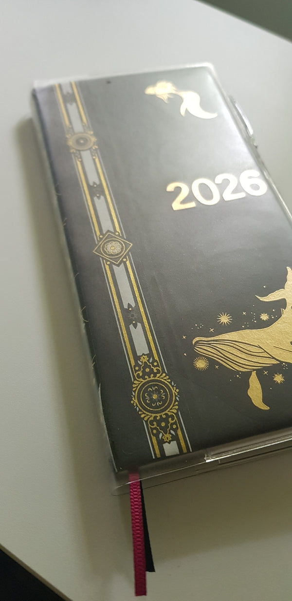 A strip of gold foil washi tape is applied to a journal