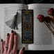 Black literati bookmark features white and gold foil design in an intricate classical book style. The bookmark has a grey tassel and sits on a classical book on a black background.