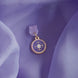 An detail shot of the wisteria literati dust plug on a light purple fabric background. The dust plug is light purple with a gold and white flower design in a circle shape.