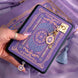 An image of the wisteria literati eReader decor bundle. The set features an eReader sleeve, eReader sticker insert, charmlet and dust plug all in the same light purple colour with pastel pink, purple and blue detailing alongside gold foil and embroidery.