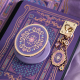 An detail shot of the wisteria literati eReader decor bundle. The set features an eReader sleeve, eReader sticker insert, charmlet and dust plug all in the same light purple colour with pastel pink, purple and blue detailing alongside gold foil and embroidery.