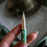 Detail image of the sage green Bibliophile pen by The Quirky Cup Collective. The light green pen features a classic book inspired design in shades of green, white and cream with gold detailing. 
