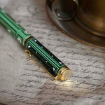 Detail image of the sage green Bibliophile pen by The Quirky Cup Collective. The light green pen features a classic book inspired design in shades of green, white and cream with gold detailing. The top of the pen cap features a small engraved flower motif.