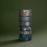The full set of the Sage green variations of the Literati washi tape by The Quirky Cup Collective sit as rolls in a stack in a green background. The classic book inspired washi tape designs feature classical book inspired designs and ornamentation in shades of dark green, sage green, white and foiled gold.