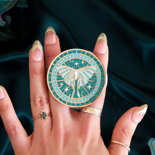 teal phone grip depicting a luna moth with celestial accents by the quirky cup collective