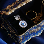 The Quirky Cup Collective Moncherie dust plug features a floral motif in a decorative french inspired style in shades of blue, cream and gold. The enamel element it attached to a transparent USB-c insert and is perfect for feminine kindle decor. The unique ereader accessory sits on a small velvet lined decorative tray on a royal blue fabric background.