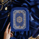 The Moncherie eReader and kindle case by The Quirky Cup Collective is the perfect feminine kindle aesthetic addition for book lovers. The blue velvet case features an intricate French inspired design in shades of gold, cream and light blue. The case also features a wrist strap with gold hardware. The case is styled on a royal blue fabric background and is surrounded by blue bookish props.