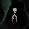 A dust plug design by The Quirky Cup Collective sits on a green fabric background. The silver Night Realm design (as part of the romantasy kindle decor release) shows an arched stained glass window motif with a moon a stars.