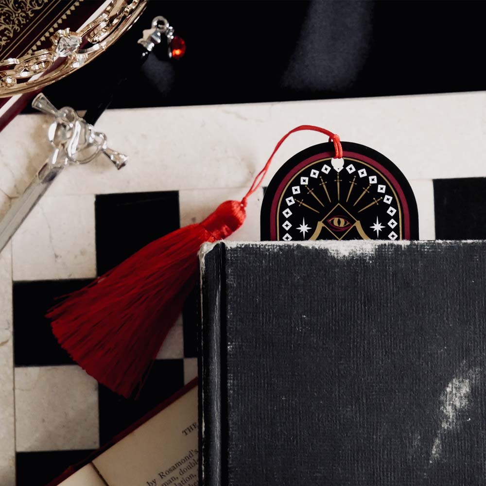 Black book with a red tassel on a checkered surface with decorative items.