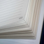 The corner detail of the Oath Breaker journal shows a tiny crown line drawing on the white lined journal pages.
