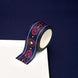 A close up of the Oath breaker washi tape by The Quirky Cup Collective. The roll of fantasy inspired washi tape is on the corner of a white journal on a blue background. The romantasy washi tape design is blue and pink with gold detailing- the intricate design showing a sword alongside geometric patterns.
