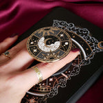 Hand holding a decorative kindle grip with celestial design against a pink fabric background
