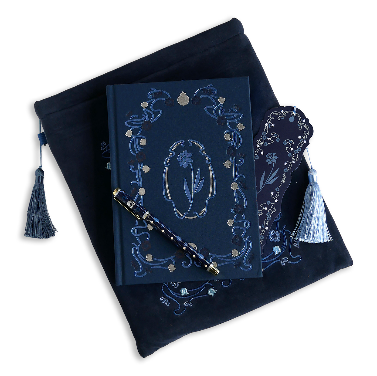 The Hades Blue Persephone journal bundle includes a book sleeve, clothbound journal, pen and bookmark all in shades of deep blue with light blue and grey detailing. All products feature the floral design with motifs of skulls and pomegranates throughout.