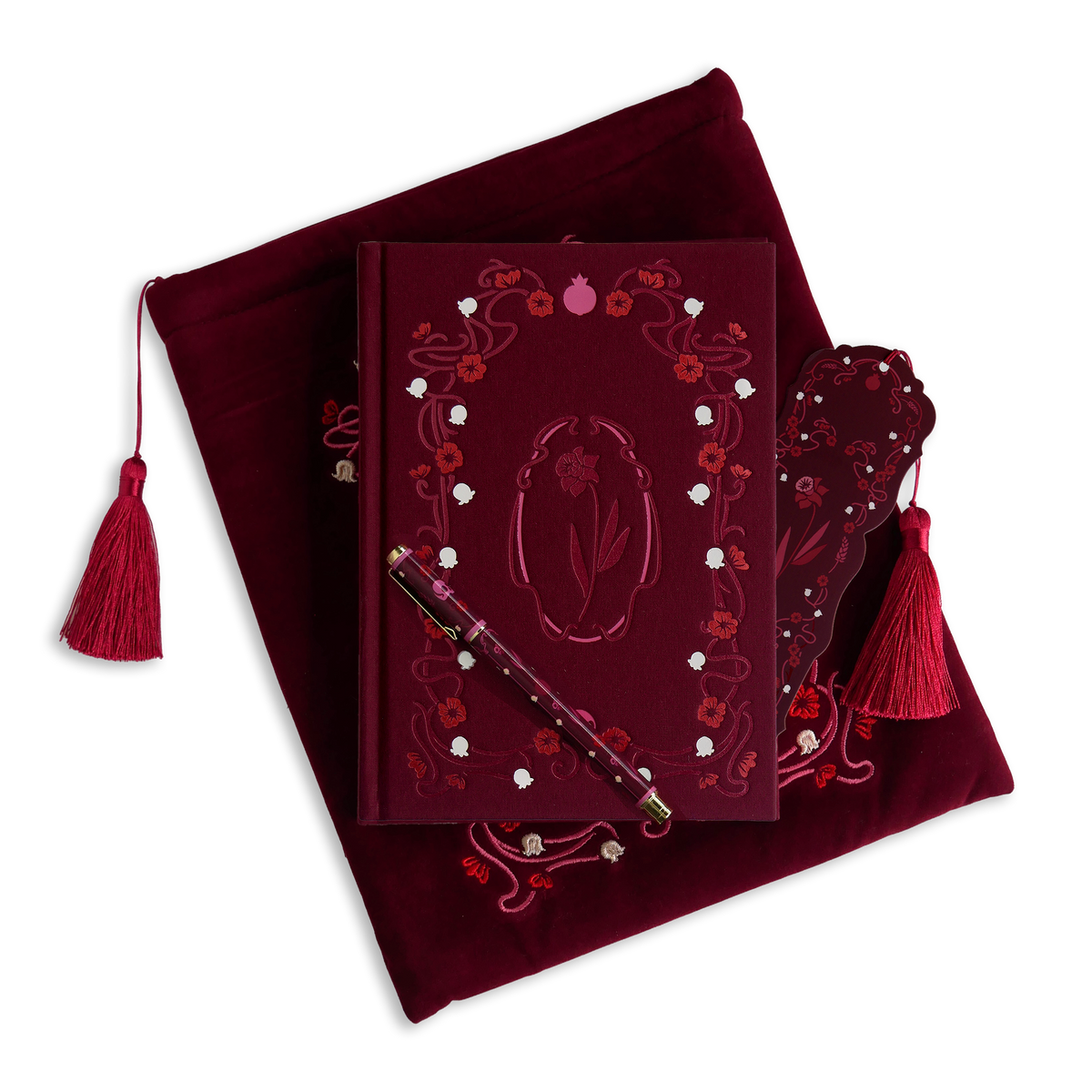 The Wine Persephone journal bundle includes a book sleeve, clothbound journal, pen and bookmark all in shades of deep burgundy with pink and white detailing. All products feature the floral design with motifs of skulls and pomegranates throughout.