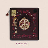 Decorated Kobo Libra with a set of aesthetic ereader accessories that are gold and wine coloured. Theme of products is Persephone and features a pomegranate, a flower, skull, daffodil, poppies and a heart. Inspired by art nouveau
