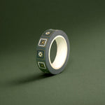 The Sage green variation of the Poetica Literati washi tape. The book inspired washi tape design is shown on a green background and features geometric flower motifs in shades of dark green, sage green and gold.