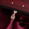 A Pomegranate dust plug design by The Quirky Cup Collective is plugged into a kindle on a deep red fabric background. Inspired by Persephone (as part of the fantasy kindle decor release) the gold dust plug features a cut pomegranate design.
