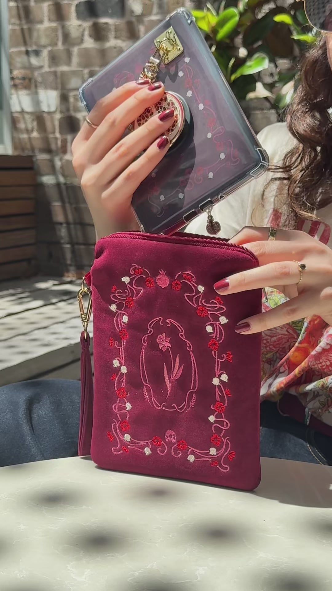 A video showing the Persephone e-reader bundle (aka a kindle decor set) by The Quirky Cup Collective in use. The embroidered kindle case, kindle insert sticker, charmlet (attached with a charm anchor) and kindle pop socket (aka a clingie) are all in shades of deep red and feature pomegranates, skulls and art nouveu inspired flower motifs.