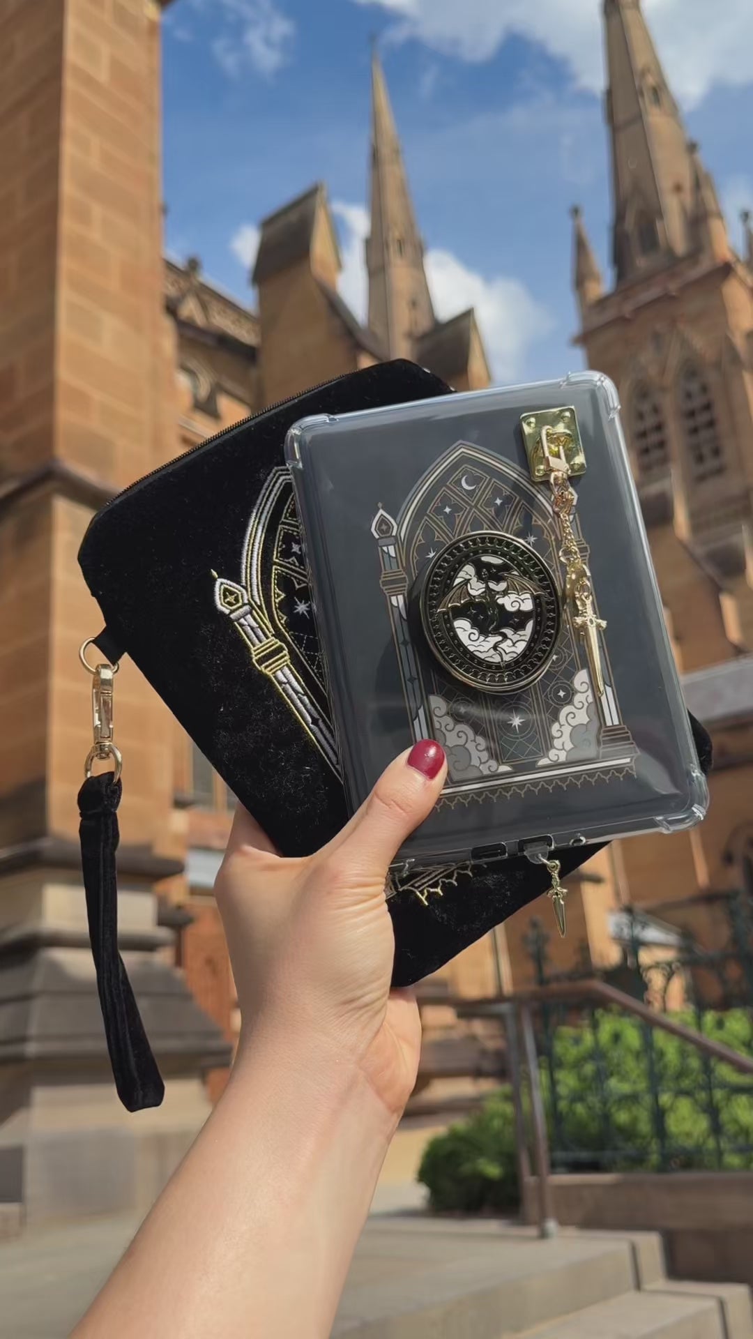 A video showing the Dragon Rider e-reader bundle (aka a kindle decor set) by The Quirky Cup Collective in use. The embroidered kindle case, kindle insert sticker, charmlet (attached with a charm anchor) and kindle pop socket (aka a clingie) feature a distinct black, white and gold aesthetic with a motif of dragons in front of a stained glass window.
