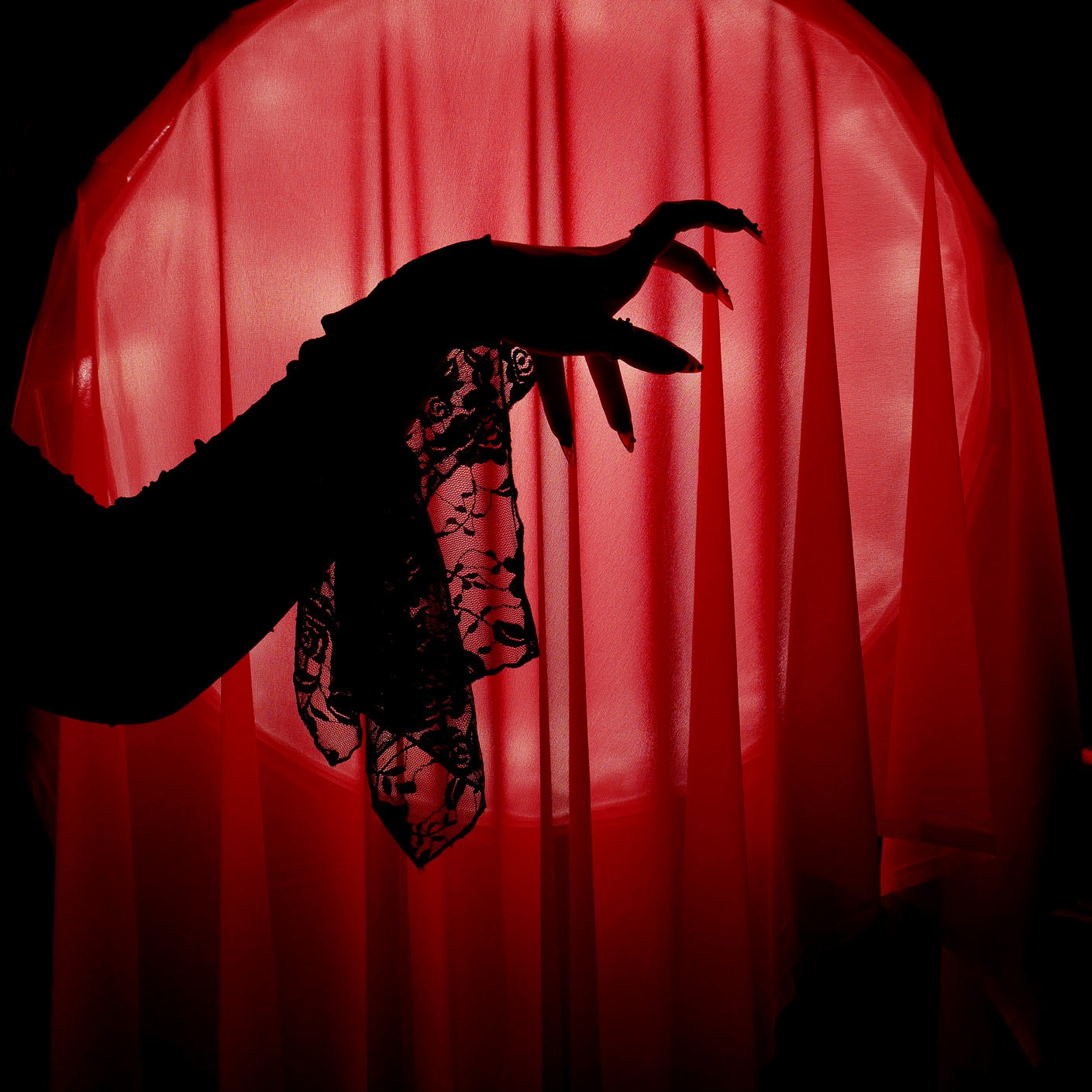 A promo image for Serpents & Swords collection by The Quirky Cup Collective, a Silhouette of a hand with long nails and a lace sleeve reaching towards a red curtain for a fantasy book aesthetic.