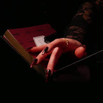 A promo image for the Serpents & Swords collection, a hand with long red nails rests their hand on an The Quirky Cup Collective journal in a dark setting.