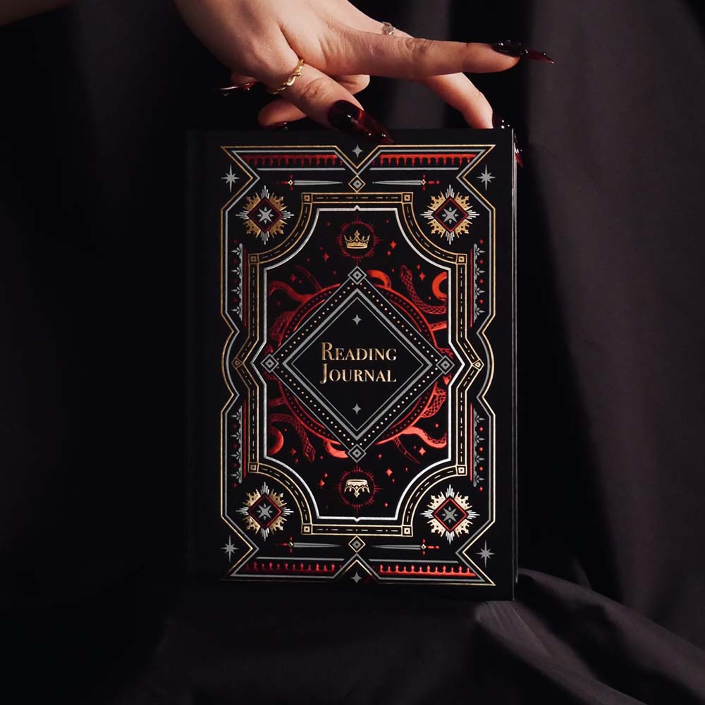 Decorative dark and moody reading journal held by a hand against a dark background