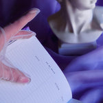 A spread of the Wisteria Lilac Reading journal by The Quirky Cup Collective sits on a soft lilac background with pearls and a dreamy, hazy aesthetic. The page shown is the To Be Read tracker table.