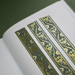The Sage green variation of the Scriptus Literati washi tape. The classic book inspired washi tape design sits as three strips on a journal page and is shown on a green background and features a classic victorian motif of flowers and curling scrolls in shades of dark green, sage green, white and foiled gold.