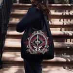 The black fantasy book inspired Serpents & Swords tote bag by The Quirky Cup Collective features a decorative emblem with crown, snake and sword motifs in red, white and gold. 