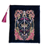 Hand holding a blue book sleeve with decorative fantasy embroidery with red background book sleeve