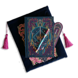 The blue Serpents & Swords bundle shows a book- sleeve, journal, pen and bookmark. Each piece features an intricate fantasy book inspired motif of a crown, sword, snakes and goblets in shades of pink, teal and gold on a deep blue background. The sleeve and bookmark also have bright pink tassles.