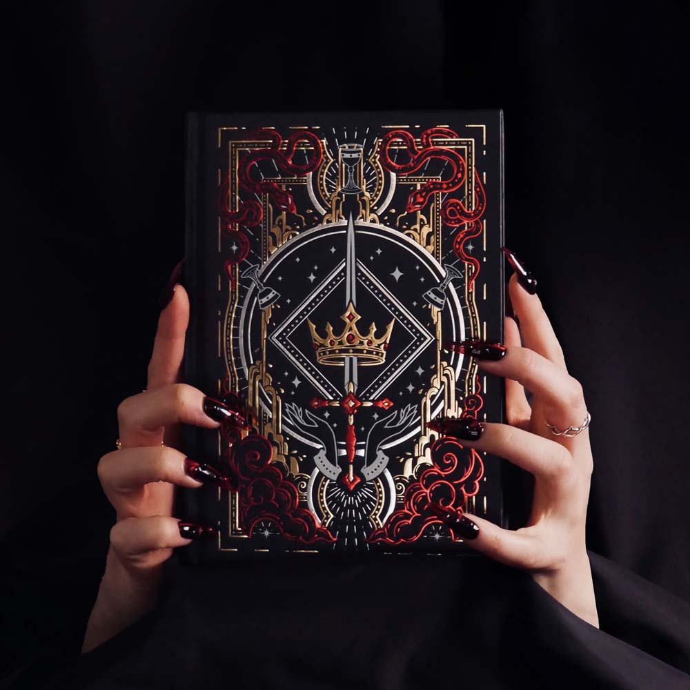 Decorative journal covered in fantasy elements held by hands against a black background