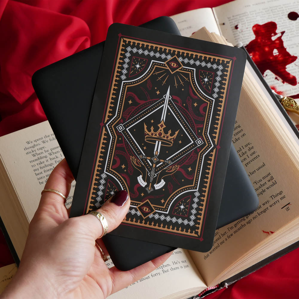 The Oath Breaker Kindle Sticker Insert by The Quirky Cup Collective shows in intricate romantasy inspired design of a sword and grown surrounded by intricate snake, star and hand motifs. The mostly black design features gold, silver, red and white detailing.