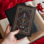 The Oath Breaker Kindle Sticker Insert by The Quirky Cup Collective shows in intricate romantasy inspired design of a sword and grown surrounded by intricate snake, star and hand motifs. The mostly black design features gold, silver, red and white detailing.