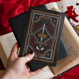 The Oath Breaker Kindle Sticker Insert by The Quirky Cup Collective shows in intricate romantasy inspired design of a sword and grown surrounded by intricate snake, star and hand motifs. The mostly black design features gold, silver, red and white detailing.