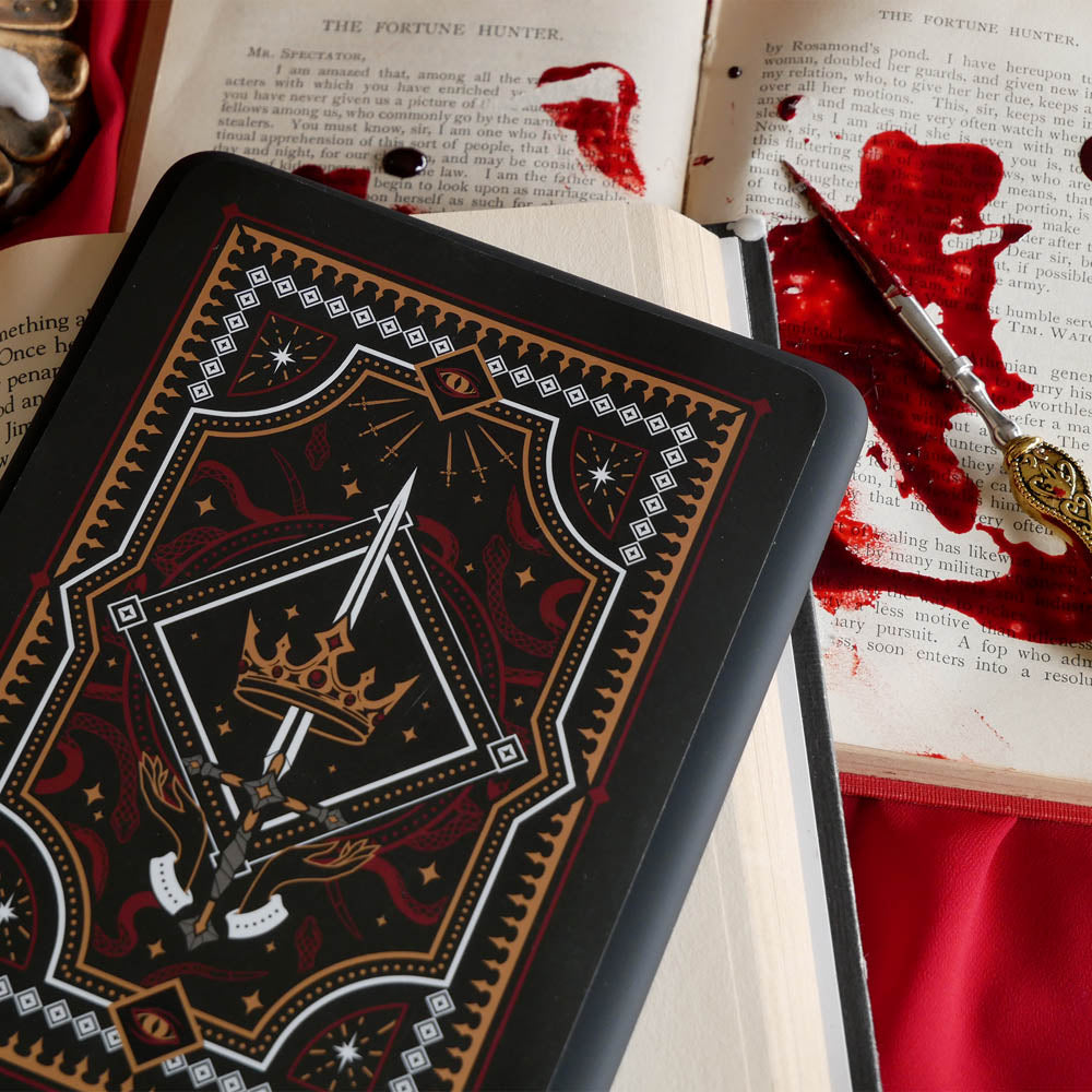 The Oath Breaker Kindle Sticker Insert by The Quirky Cup Collective shows in intricate romantasy inspired design of a sword and grown surrounded by intricate snake, star and hand motifs. The mostly black design features gold, silver, red and white detailing.