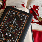 The Oath Breaker Kindle Sticker Insert by The Quirky Cup Collective shows in intricate romantasy inspired design of a sword and grown surrounded by intricate snake, star and hand motifs. The mostly black design features gold, silver, red and white detailing.