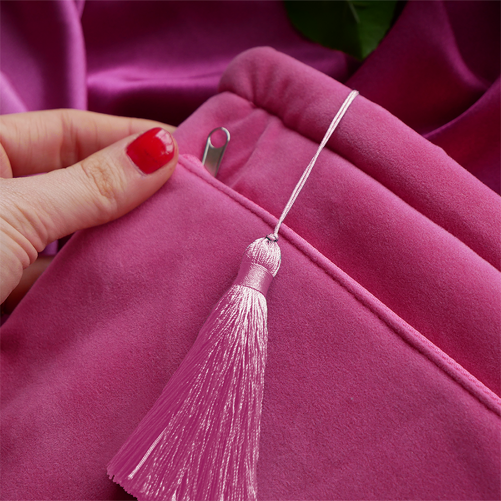 pink velvet sleeve on a background of pink satin. Laid across the sleeve is a pink tassel

