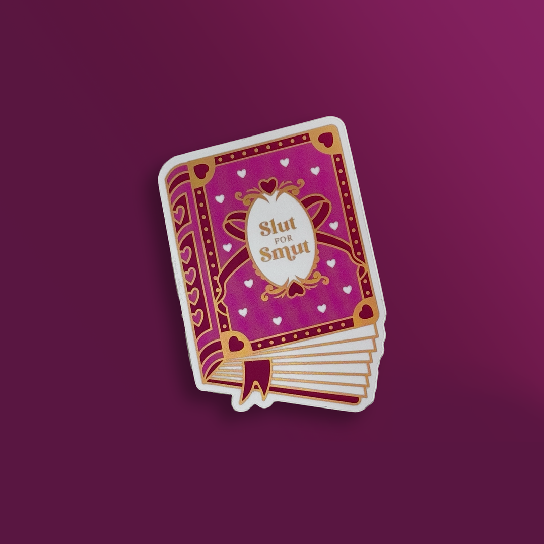 sticker on a pink background. Sticker is in the shape of a book that has a pink cover with pink and white hearts, a bow and gold accents