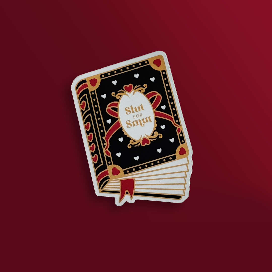 sticker on a red background. Sticker is in the shape of a book that has a black cover with red and white hearts, a bow and gold accents