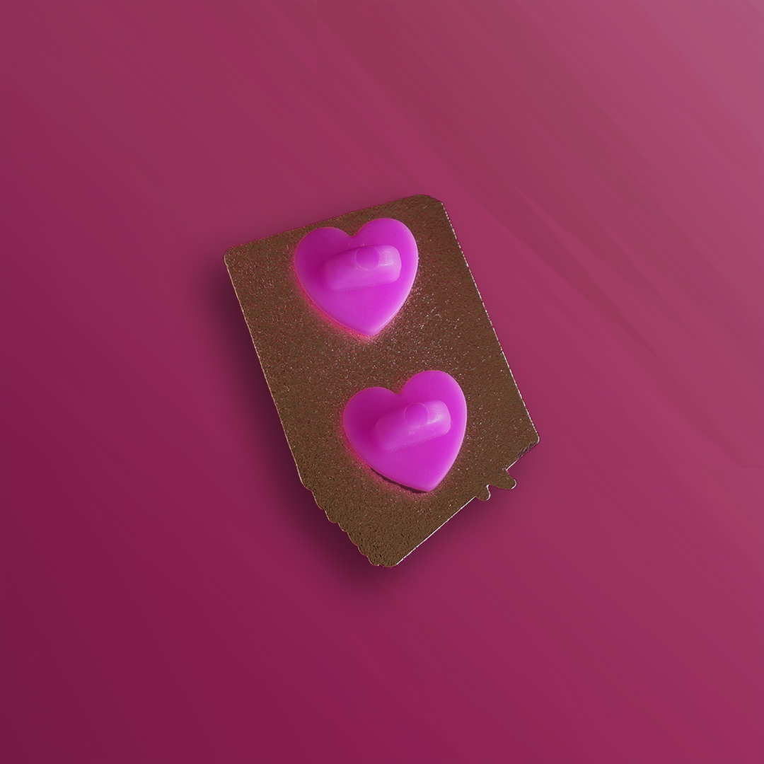 The reverse side of an enamel pin showing two backing posts with rubber heart stoppers