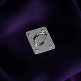 A The Quirky Cup Collective charm anchor on a dark purple fabric background. The silver rectangle shaped clip is used to attach Charmlets to flat surfaces (such as your device).