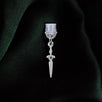 A dust plug design by The Quirky Cup Collective sits on a green fabric background. The silver sword design (as part of the romantasy e-reader decor release) shows a small gold dagger with black detailing.